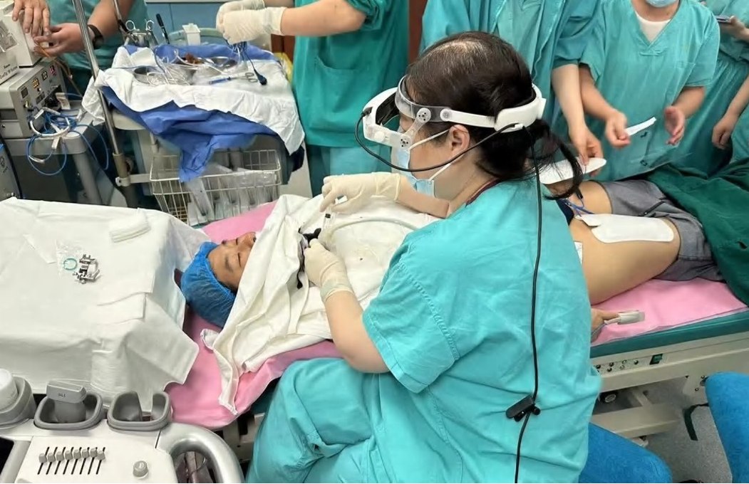 Clinician wearing the BB Medical headset in a procedure setting with medical staff and a patient