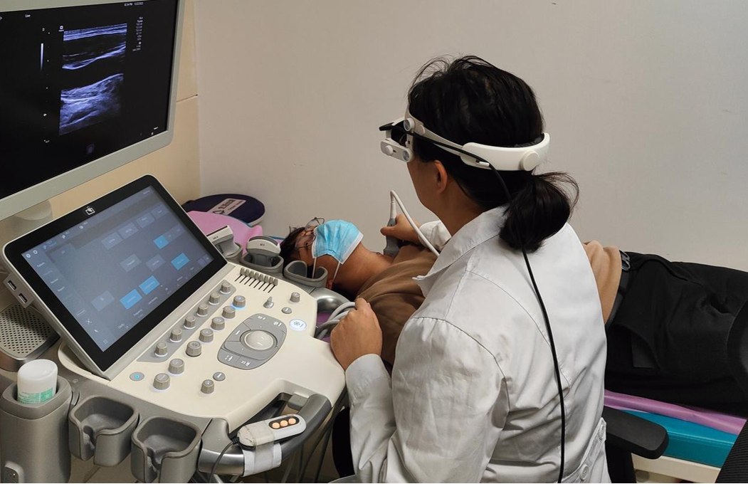 Clinician wearing the BB Medical headset while operating an ultrasound system beside a patient